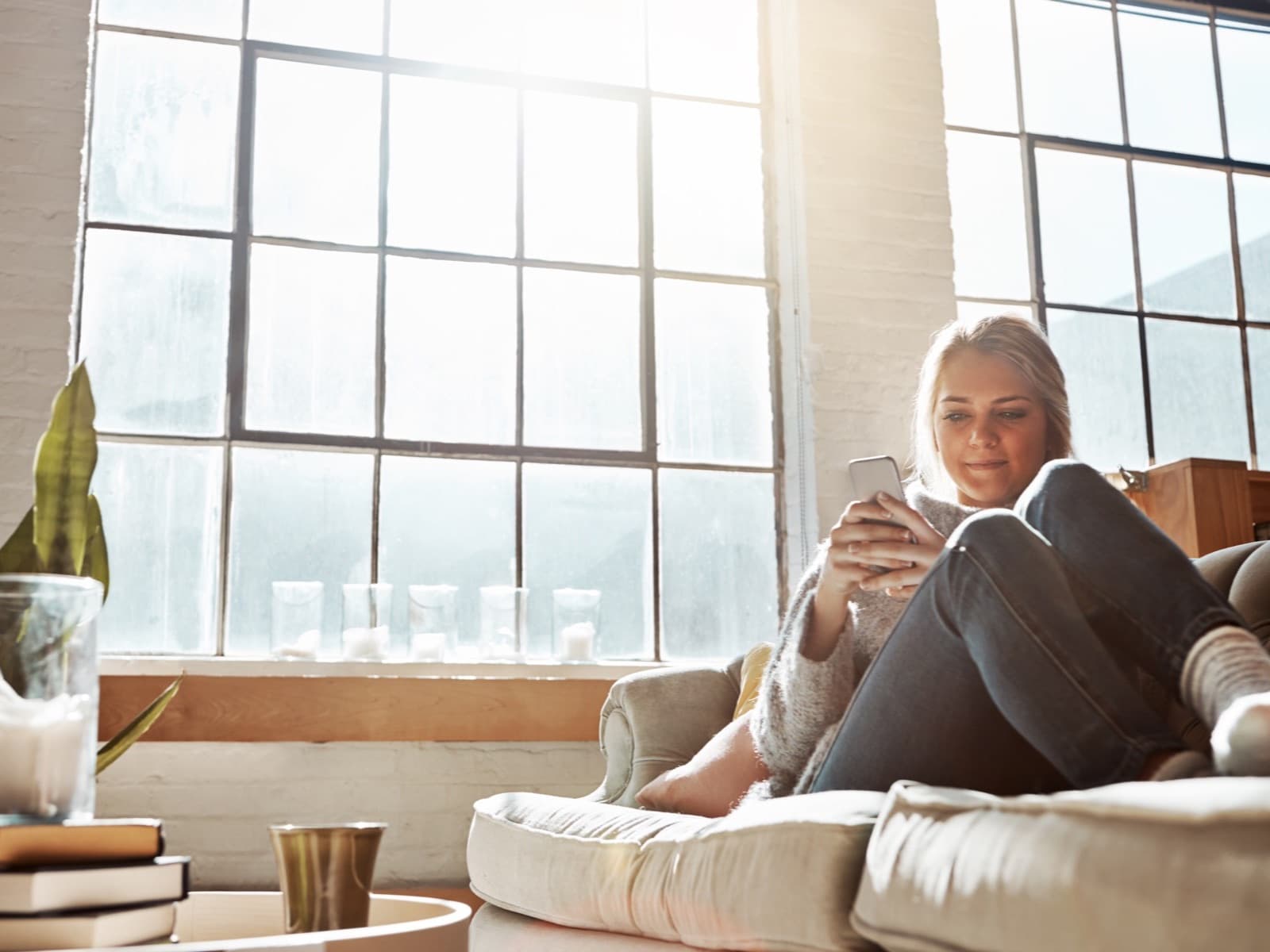 Relaxed woman messaging on mobile device indoors.
