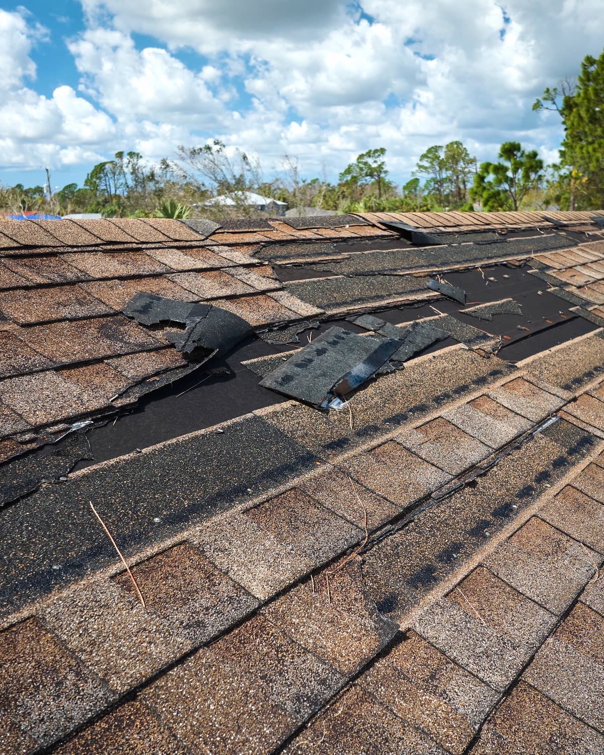 Damaged house roof with missing shingles after.