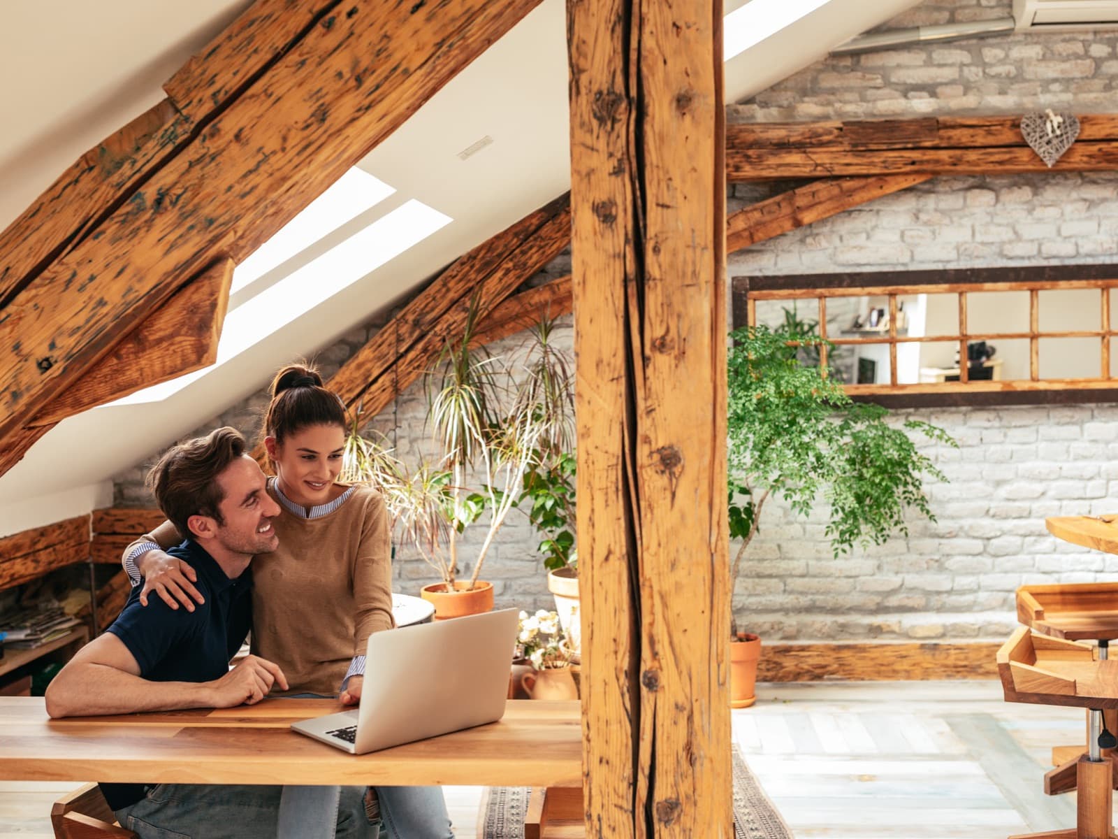 Affectionate couple using laptop in rustic home.