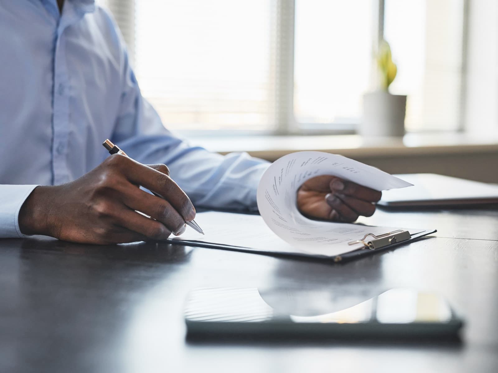 Black businessman signing document at desk in offi.
