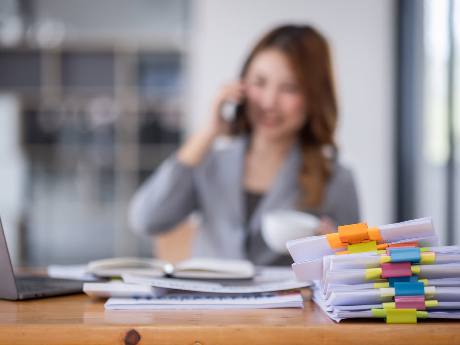Professional woman talking on phone at office desk.