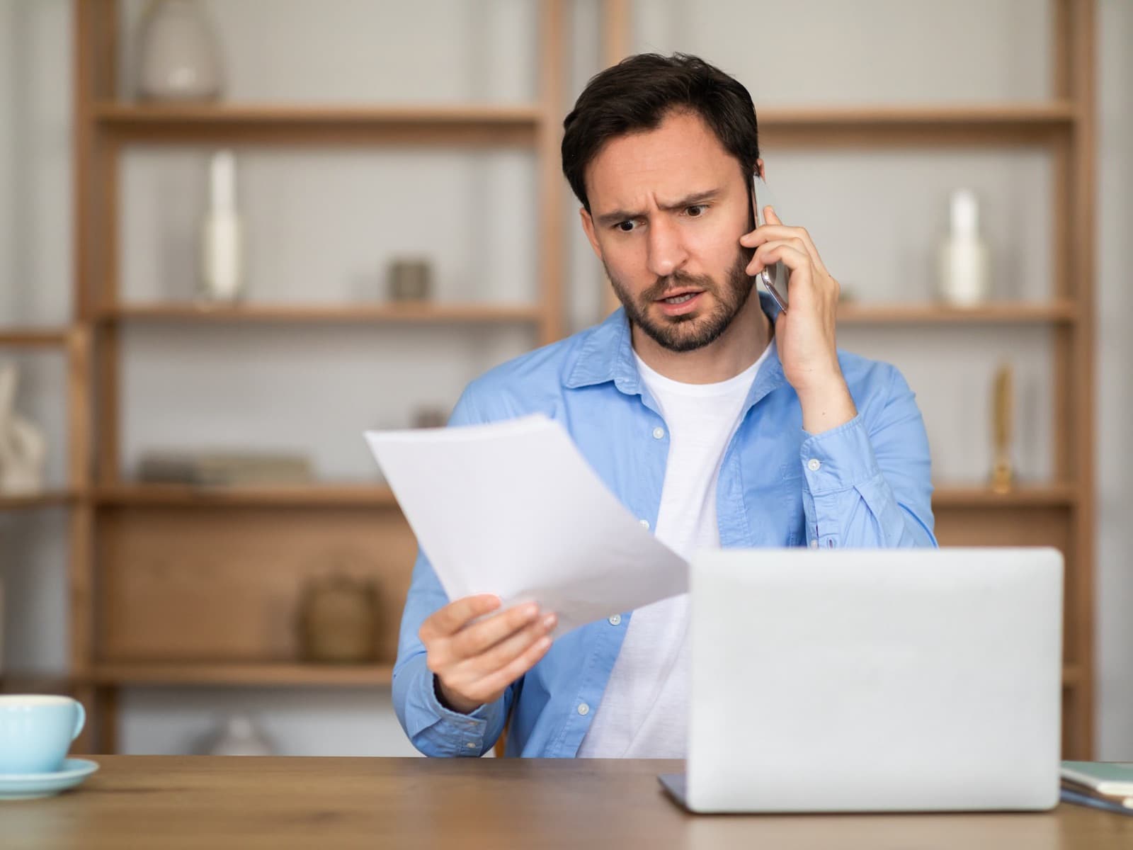 Concerned man reviewing document while on phone.