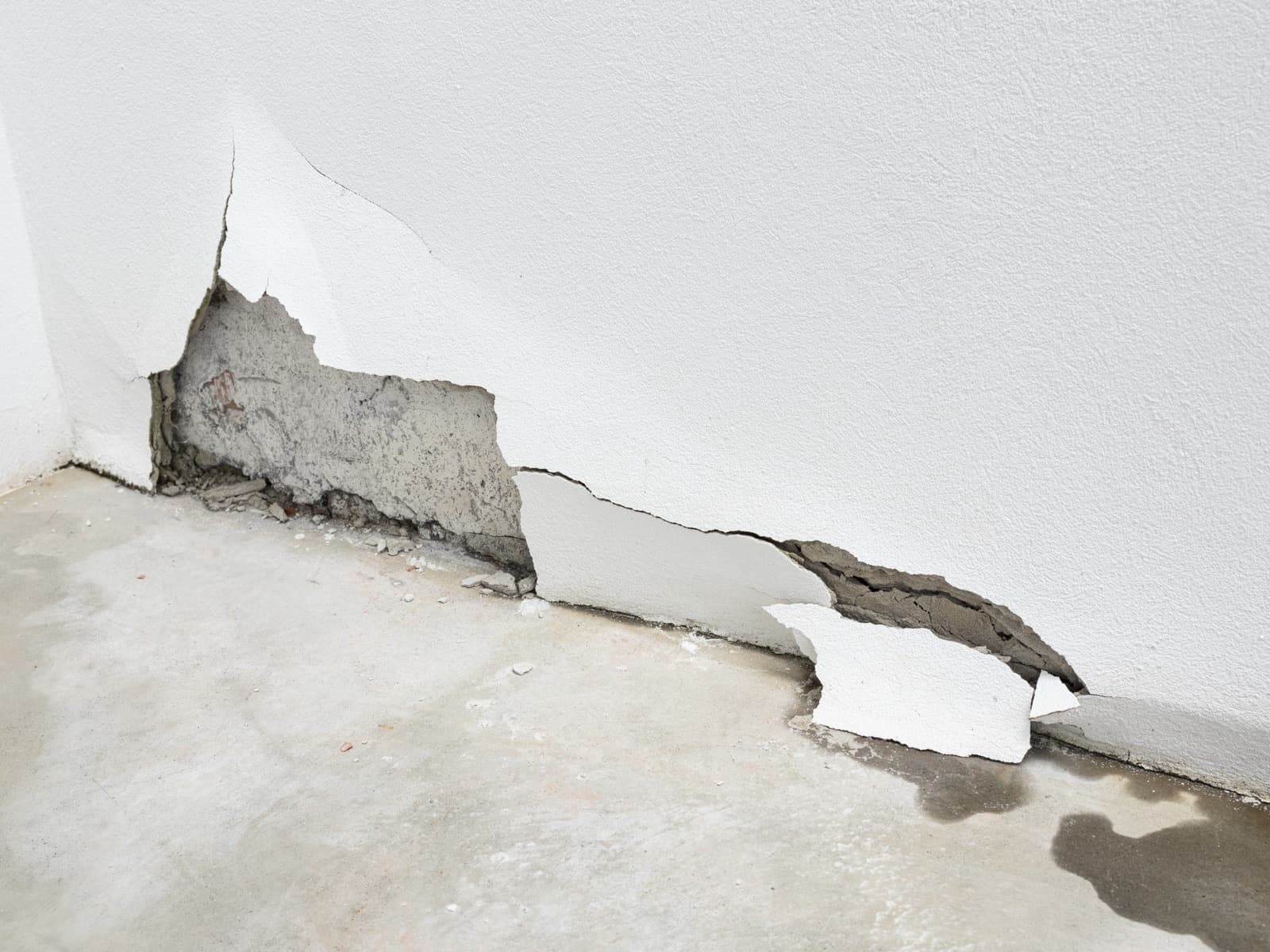 Damaged wall with plaster falling off in corner.
