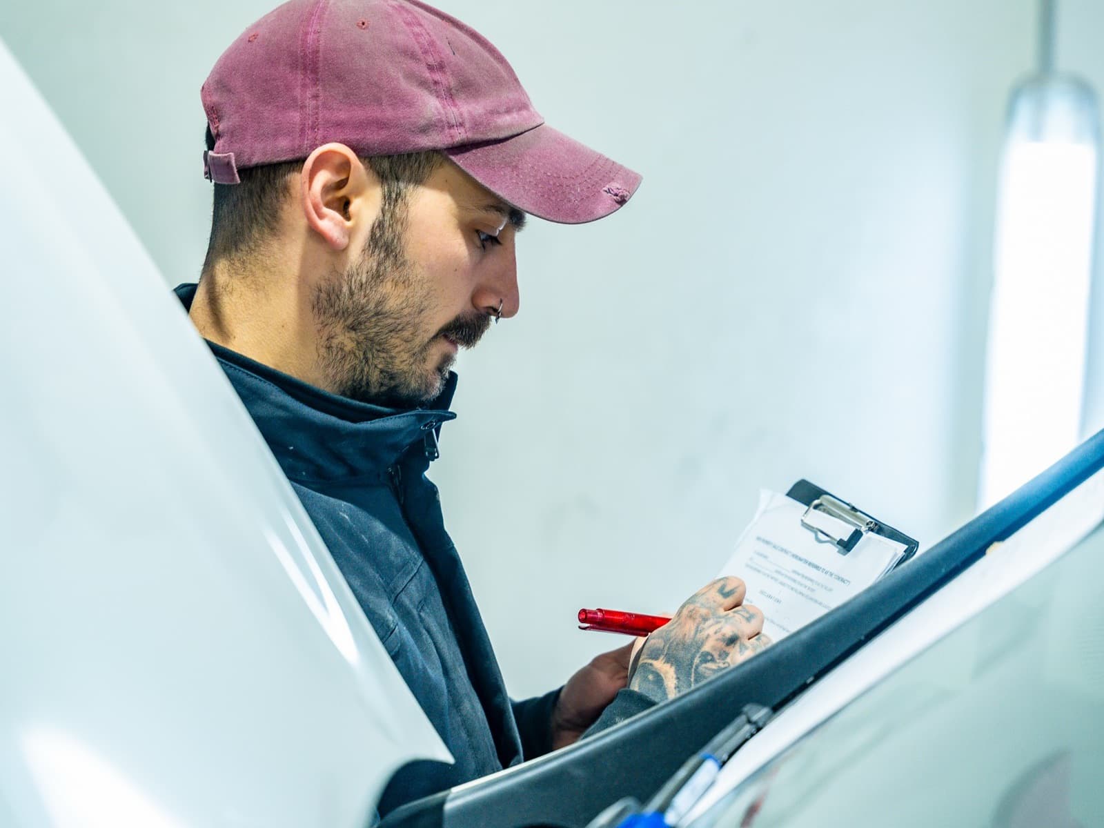 Worker inspects vehicle while holding clipboard.