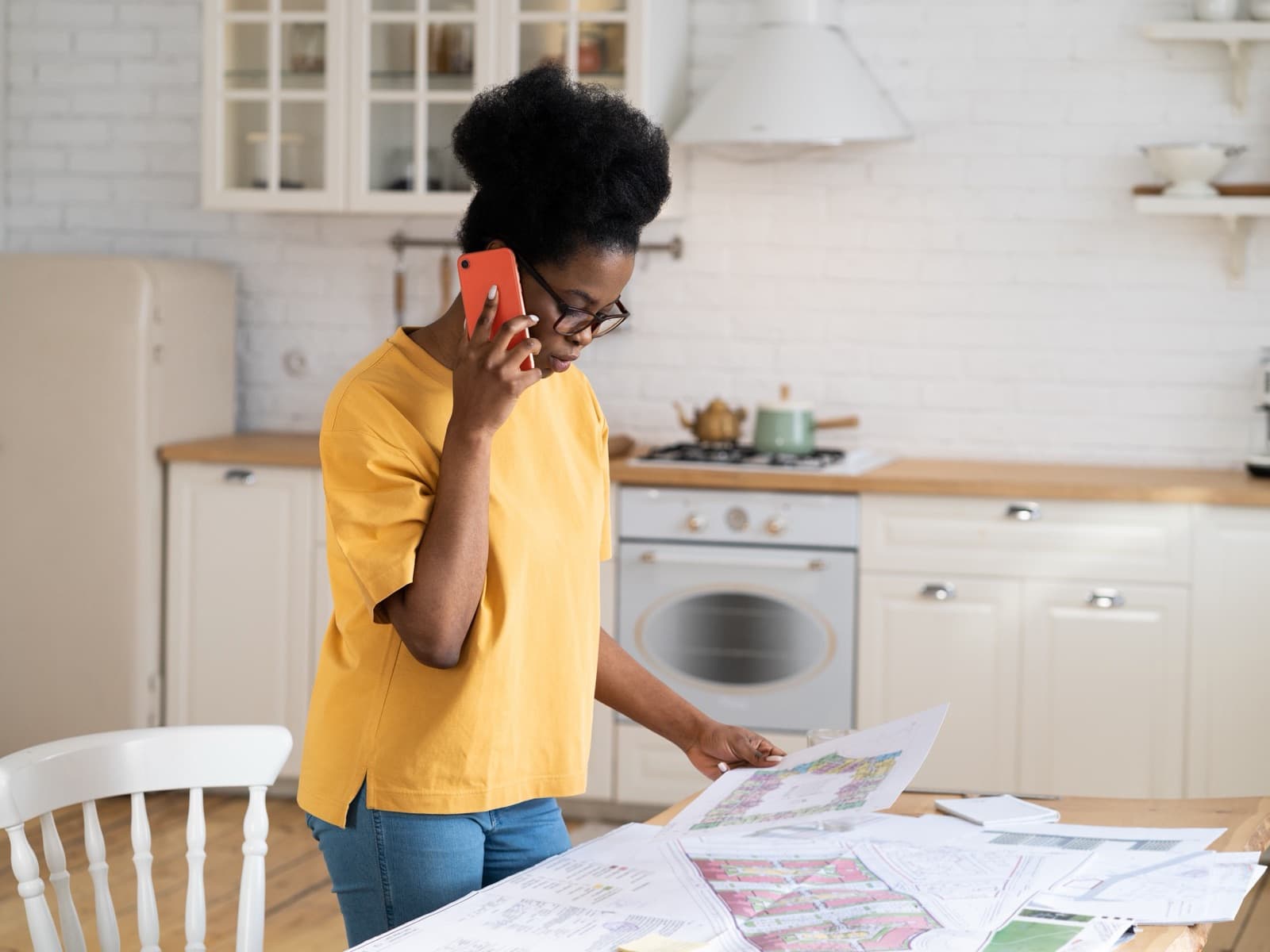 Woman reviewing blueprints and on a phone call.